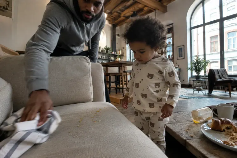 Dans un loft lyonnais, des gouttes de jus d’orange perlent sur l’assise d’un canapé beige pendant qu’un père attrape un torchon
