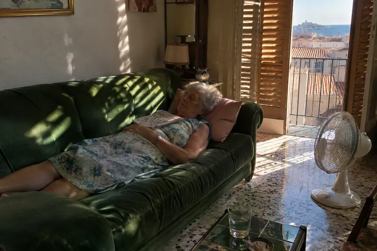 Une grand-mère fait la sieste, des mots croisés sur la poitrine, sur un canapé en velours vert émeraude dans un appartement marseillais des années 70